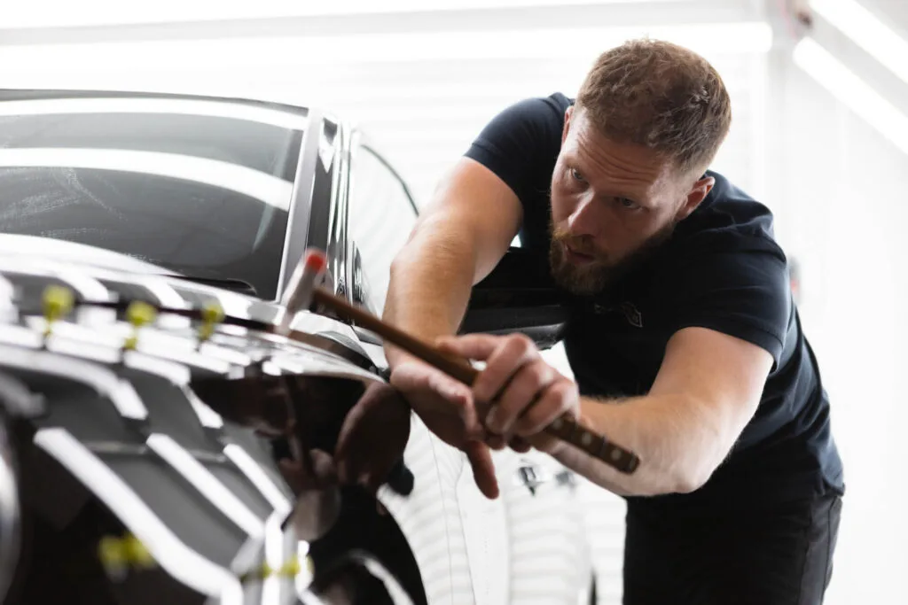 Paintless dent repair technician using PDR tools to fix minor car dents at The Dent Brothers Australia